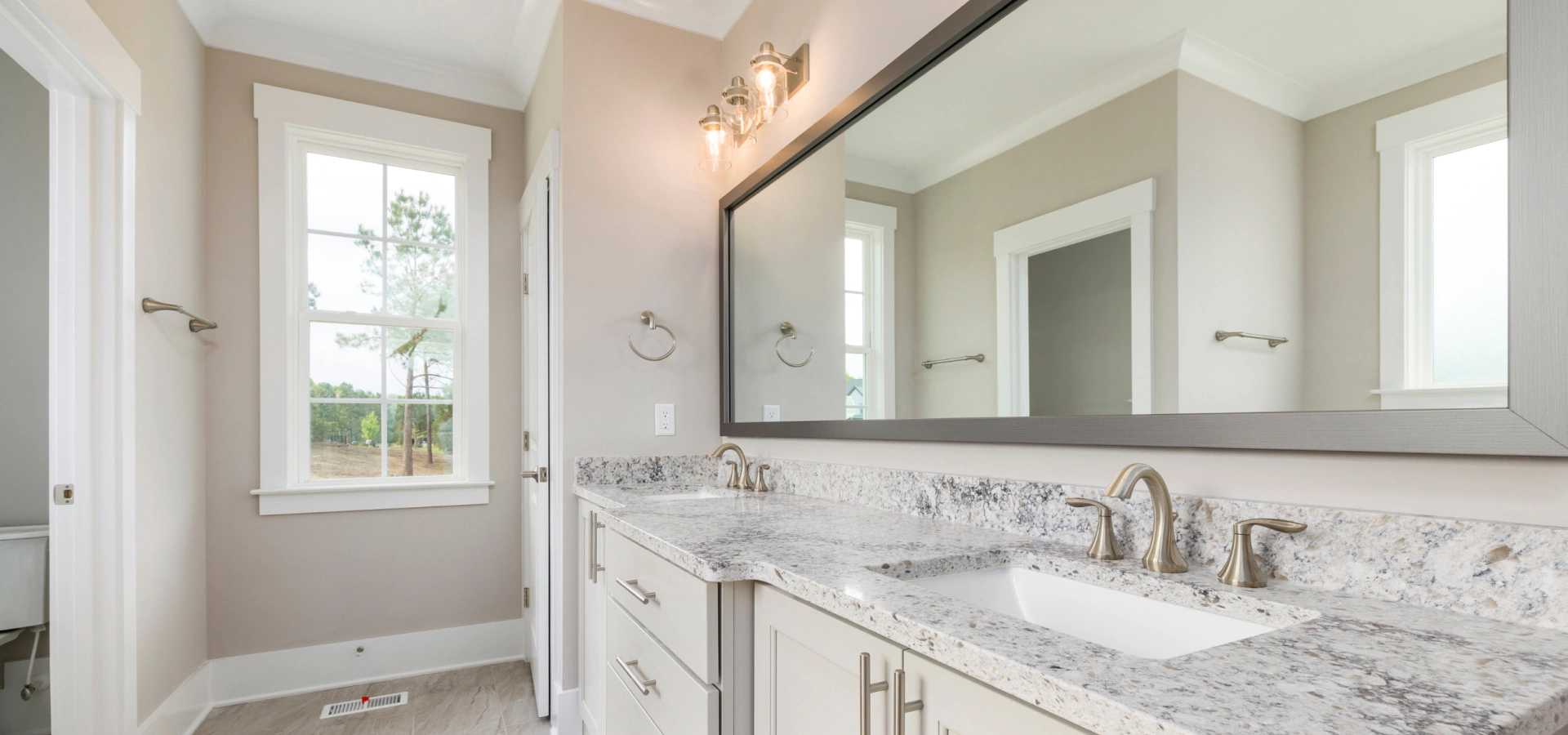custom bathroom remodeling with wide mirror and lights over cabinets and countertop